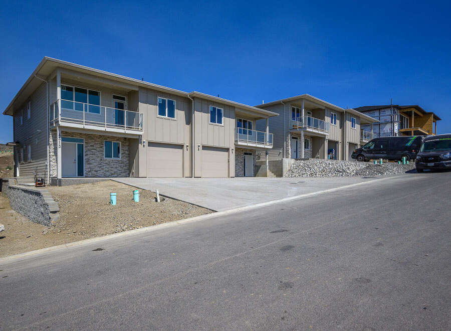 Discover modern living in these newly constructed townhomes, featuring sleek beige siding and stone accents.