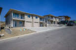 Discover modern living in these newly constructed townhomes, featuring sleek beige siding and stone accents.