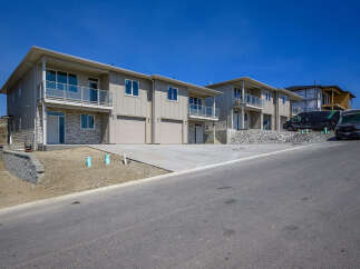 Discover modern living in these newly constructed townhomes, featuring sleek beige siding and stone accents.