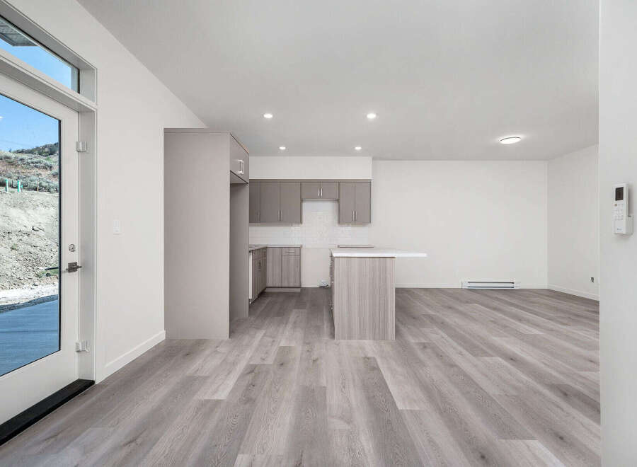 Discover modern living in this bright and airy open-concept space, featuring a sleek kitchen with ample cabinet storage and a central island perfect for meal prep and casual dining.