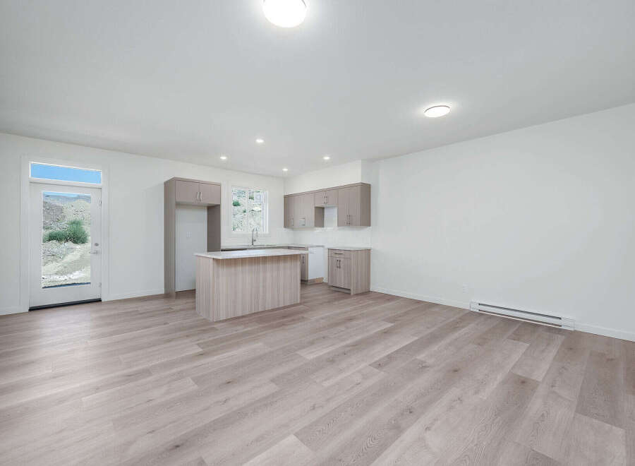 Discover modern living in this bright and airy open-concept space, featuring a sleek kitchen with ample cabinet storage and a central island perfect for meal prep and casual dining.