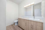 This modern bathroom features a sleek vanity with ample storage and a clean white sink, complemented by a large, illuminated mirror.