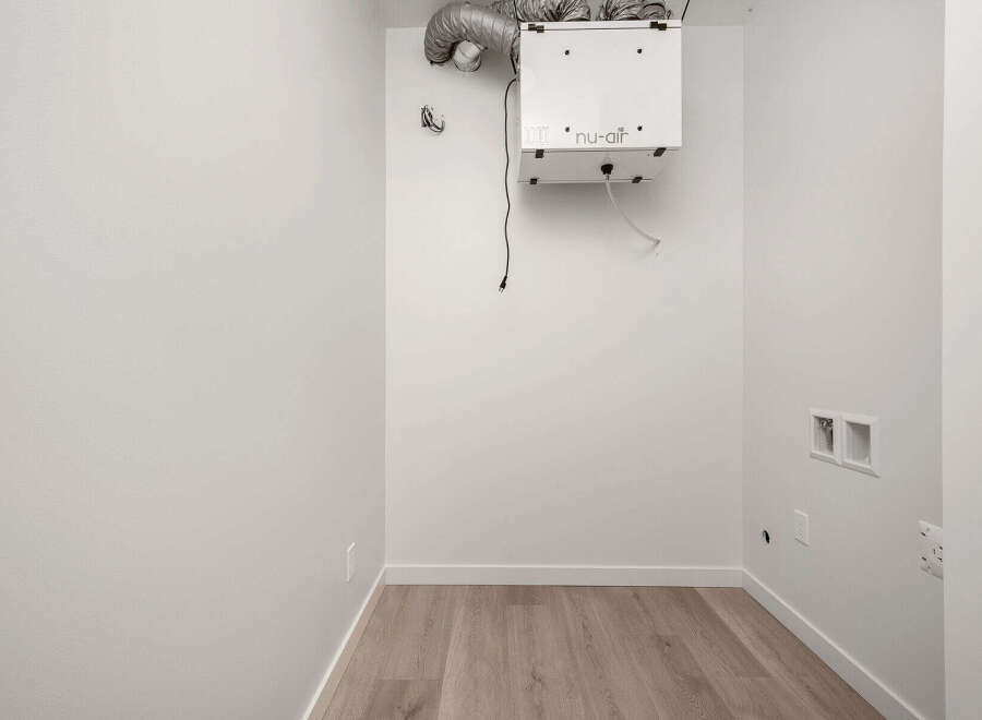 This laundry room is ready for your appliances, featuring a modern ventilation system for optimal air quality.