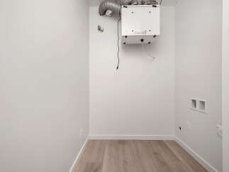 This laundry room is ready for your appliances, featuring a modern ventilation system for optimal air quality.