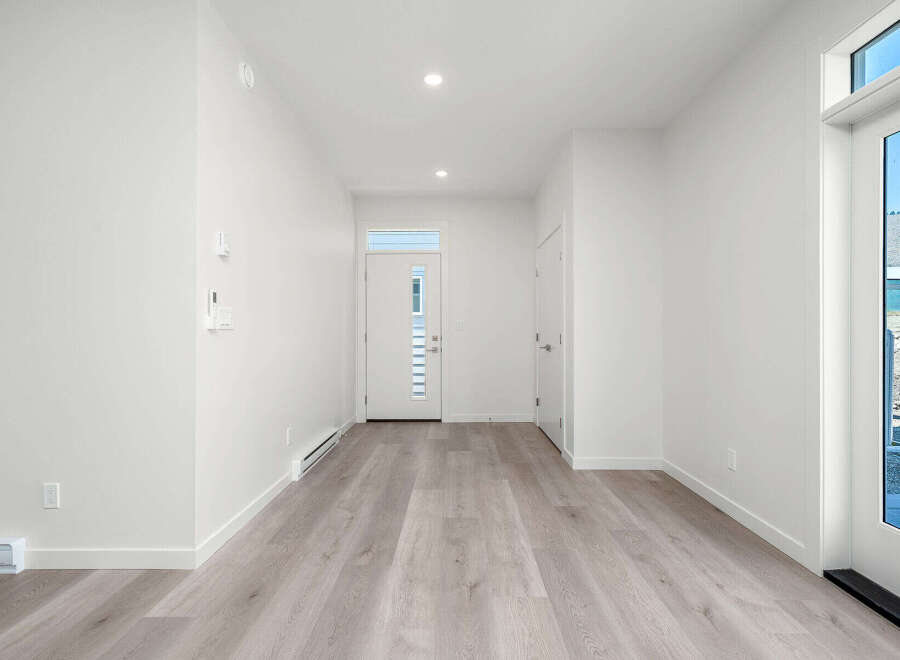 Step into this bright and airy entryway, featuring modern light wood flooring and crisp white walls.