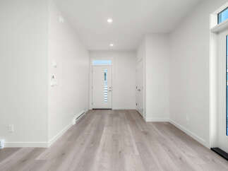 Step into this bright and airy entryway, featuring modern light wood flooring and crisp white walls.