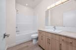This modern bathroom features a pristine white bathtub and shower combo, complemented by a sleek toilet.