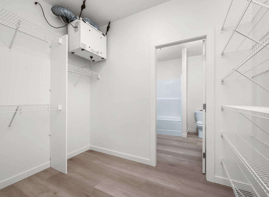 Discover ample storage in this spacious walk-in closet, featuring extensive wire shelving and a convenient ventilation system.