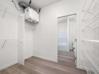 Discover ample storage in this spacious walk-in closet, featuring extensive wire shelving and a convenient ventilation system.