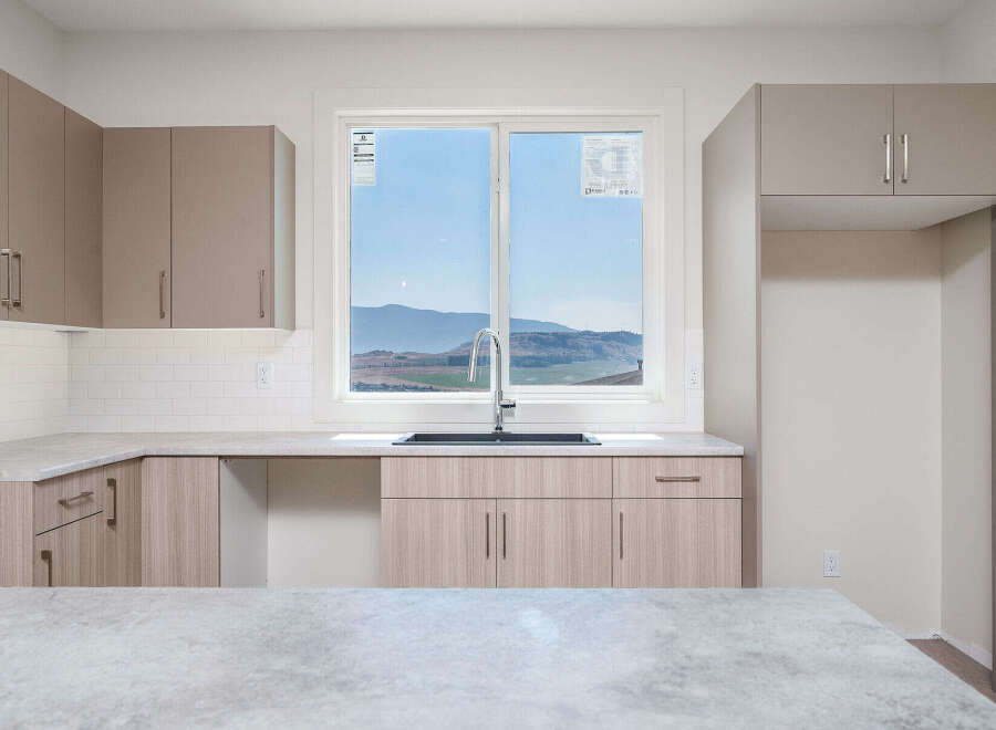 Experience modern living in this stunning kitchen featuring sleek cabinetry and a large window with breathtaking mountain views.
