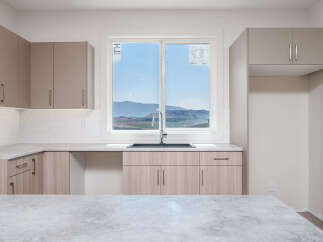 Experience modern living in this stunning kitchen featuring sleek cabinetry and a large window with breathtaking mountain views.