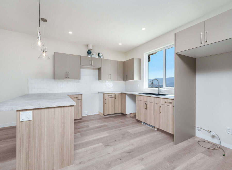 Discover this modern kitchen featuring sleek, dual-toned cabinetry and a spacious island with a granite countertop.