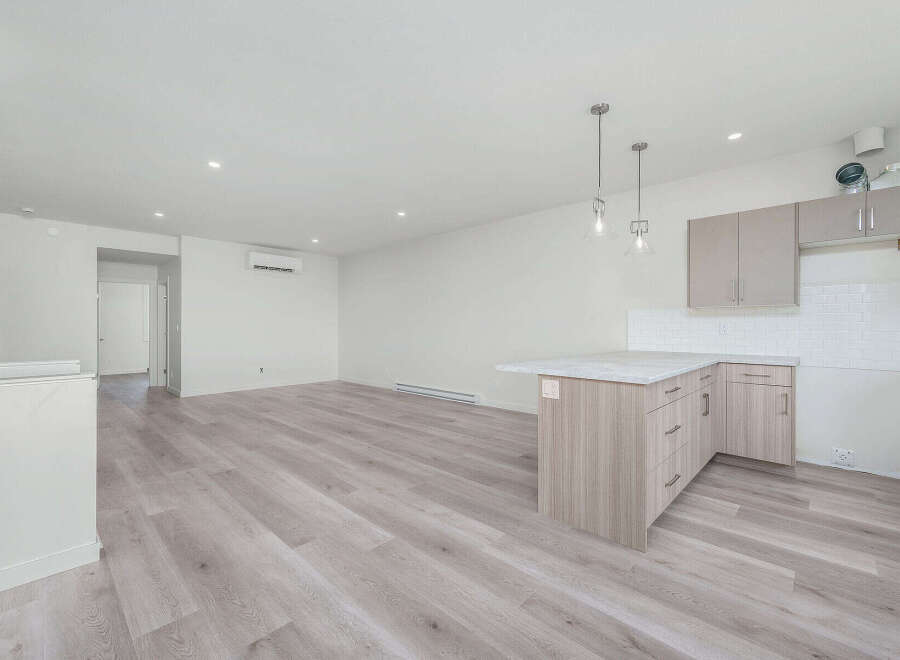 Discover modern living in this spacious open-concept apartment featuring a sleek kitchen island with ample counter space and contemporary cabinetry.