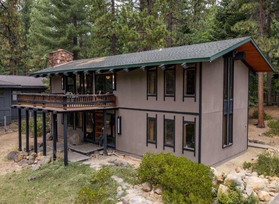 Nestled among tall pine trees, this unique home offers a striking architectural design with a spacious wooden deck perfect for enjoying the serene surroundings.