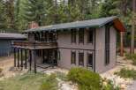 Nestled among tall pine trees, this unique home offers a striking architectural design with a spacious wooden deck perfect for enjoying the serene surroundings.