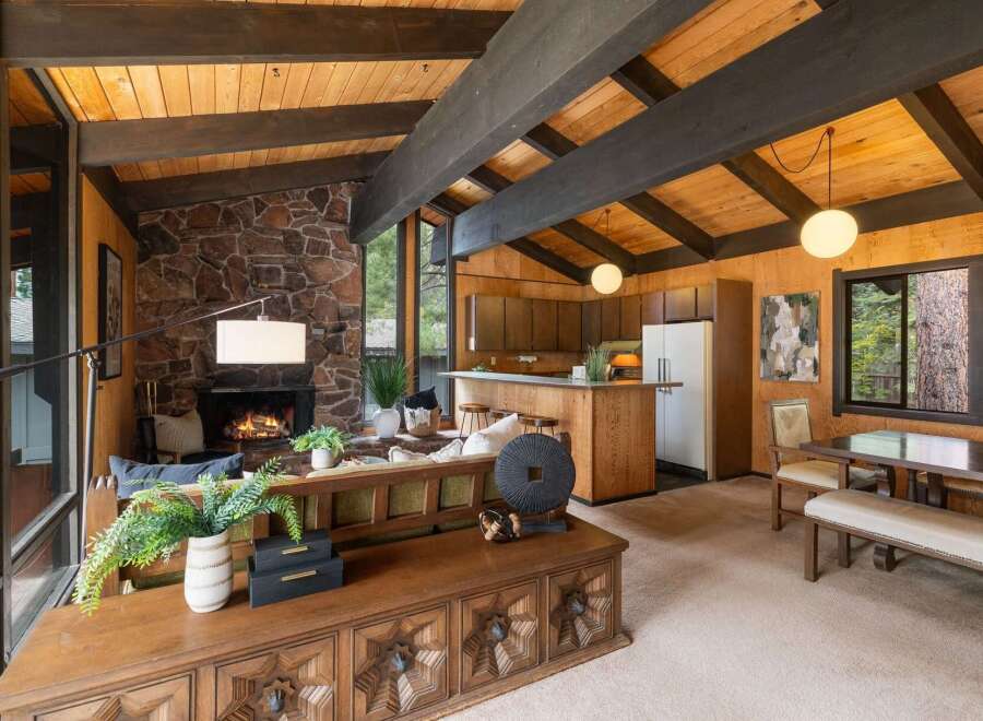 Experience rustic charm in this open-concept living space, featuring a striking stone fireplace and exposed wooden beams that create a warm, inviting atmosphere.