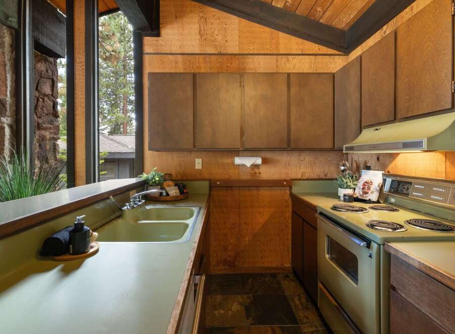 Step into a retro-inspired kitchen featuring a charming avocado green double sink and matching stove, perfect for those who appreciate vintage aesthetics.