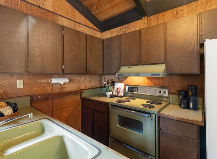Step into a charming kitchen featuring warm wood paneling and a vaulted ceiling with exposed beams.