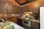 Step into a charming kitchen featuring warm wood paneling and a vaulted ceiling with exposed beams.