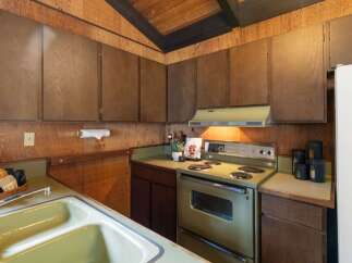 Step into a charming kitchen featuring warm wood paneling and a vaulted ceiling with exposed beams.
