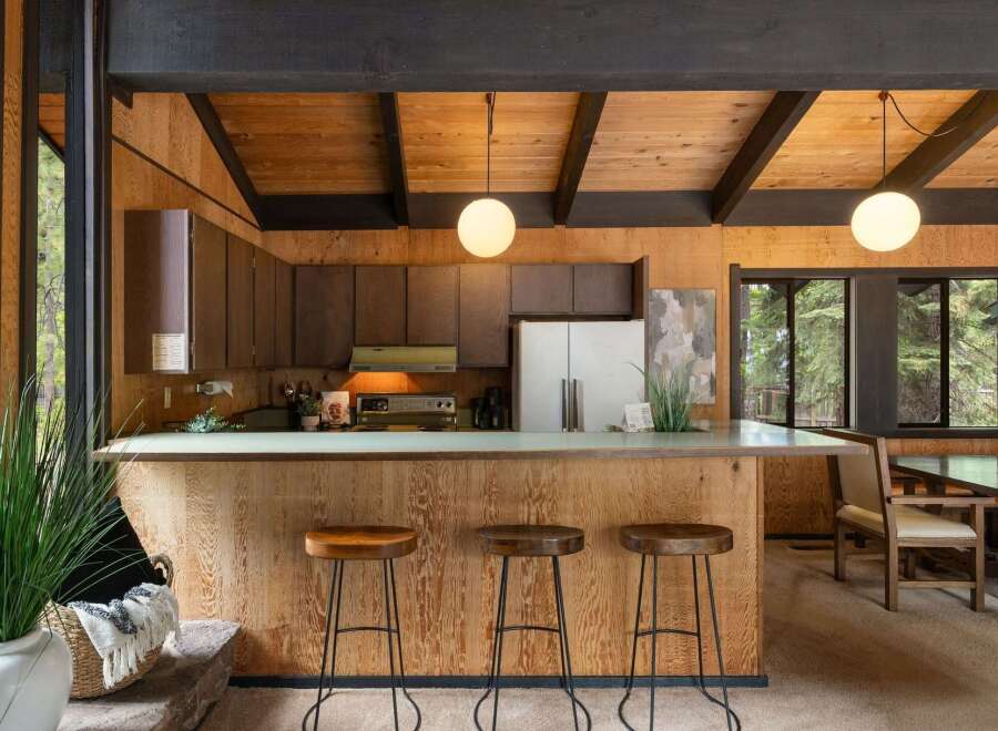 Experience rustic charm in this kitchen featuring warm wood paneling and a spacious breakfast bar perfect for casual dining.