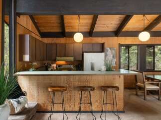 Experience rustic charm in this kitchen featuring warm wood paneling and a spacious breakfast bar perfect for casual dining.