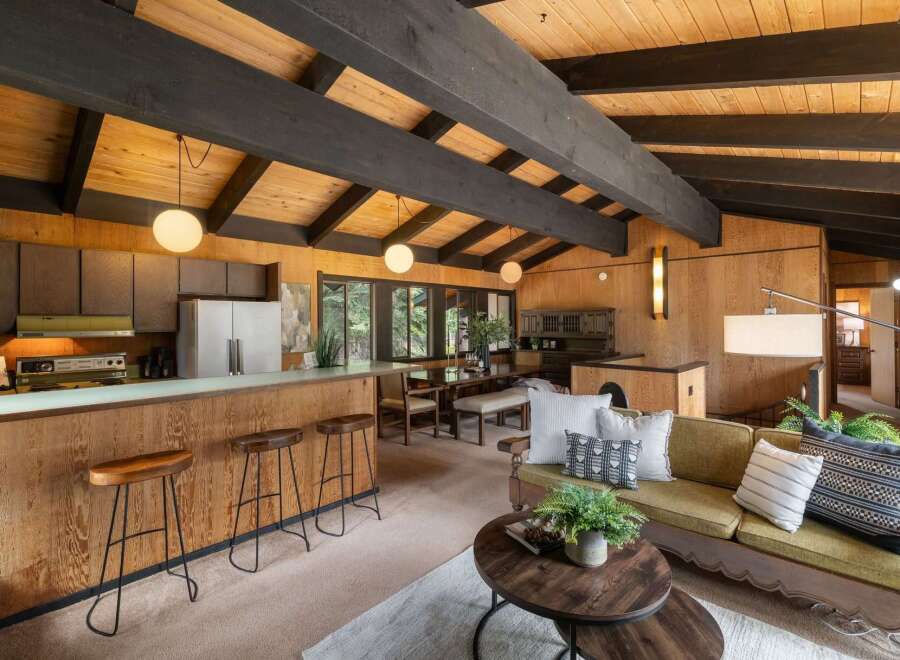Experience the warmth of this mid-century modern living space, featuring a stunning wood-paneled interior and exposed beam ceiling.