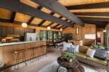 Experience the warmth of this mid-century modern living space, featuring a stunning wood-paneled interior and exposed beam ceiling.