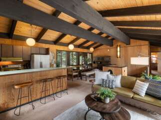 Experience the warmth of this mid-century modern living space, featuring a stunning wood-paneled interior and exposed beam ceiling.