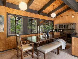 This dining room features a rustic charm with its wood-paneled walls and beamed ceiling.