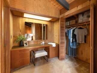 Discover this charming bedroom featuring a built-in vanity with ample storage and a large mirror, perfect for your morning routine.