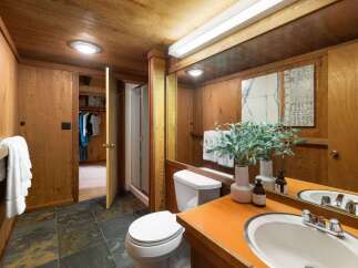 This rustic bathroom features warm wood paneling throughout, creating a cozy and natural ambiance.