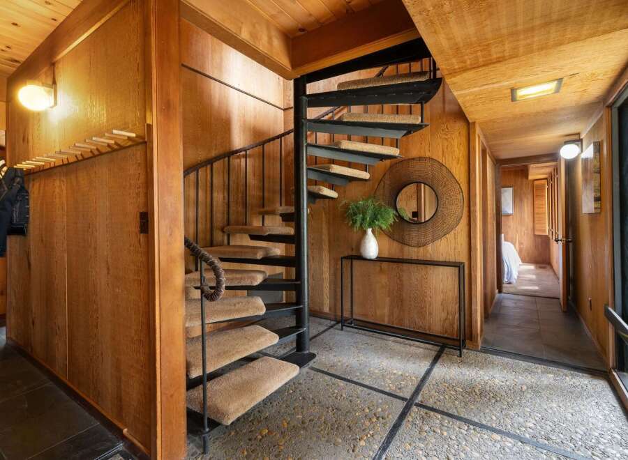 Step into a unique entryway featuring a striking spiral staircase with carpeted treads and a dark metal railing.