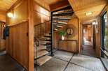Step into a unique entryway featuring a striking spiral staircase with carpeted treads and a dark metal railing.