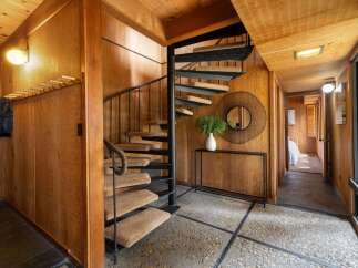 Step into a unique entryway featuring a striking spiral staircase with carpeted treads and a dark metal railing.