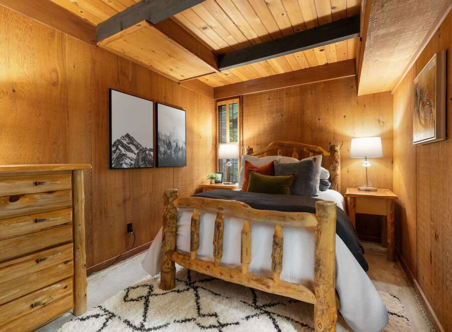 Experience rustic charm in this cozy bedroom, featuring a beautiful log bed and warm wood-paneled walls.