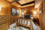 Experience rustic charm in this cozy bedroom, featuring a beautiful log bed and warm wood-paneled walls.