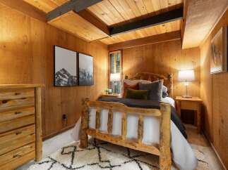 Experience rustic charm in this cozy bedroom, featuring a beautiful log bed and warm wood-paneled walls.