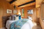 This cozy bedroom features warm wood paneling and a sloped wood-paneled ceiling with exposed beams.