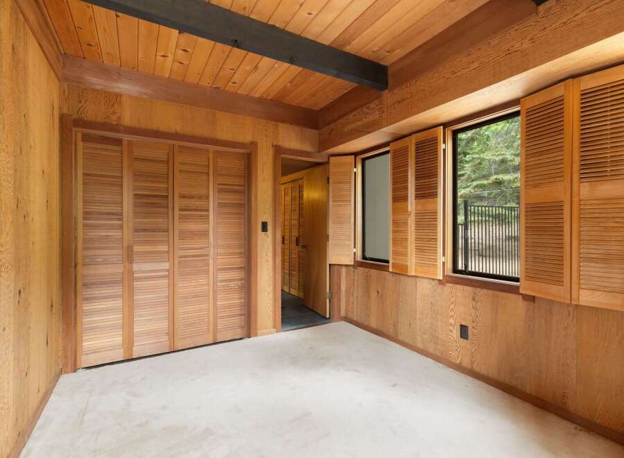 Step into a warm and inviting room featuring rich wood paneling on the walls and ceiling, complemented by a dark wood beam accent.