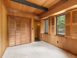 Step into a warm and inviting room featuring rich wood paneling on the walls and ceiling, complemented by a dark wood beam accent.