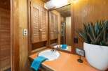 This bathroom features a charming vanity with a white sink and a vibrant orange countertop, complemented by louvered wood cabinets for ample storage.