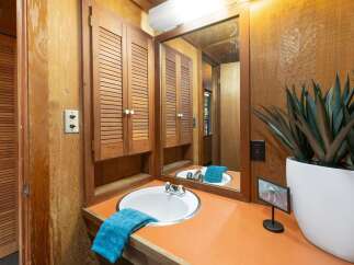 This bathroom features a charming vanity with a white sink and a vibrant orange countertop, complemented by louvered wood cabinets for ample storage.