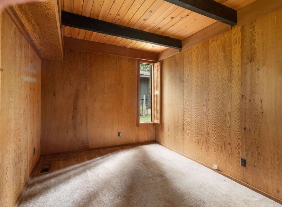 Step into a room with a warm and inviting ambiance, featuring rich wood-paneled walls and a vaulted ceiling with exposed dark beams.