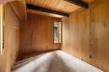 Step into a room with a warm and inviting ambiance, featuring rich wood-paneled walls and a vaulted ceiling with exposed dark beams.