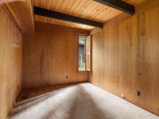 Step into a room with a warm and inviting ambiance, featuring rich wood-paneled walls and a vaulted ceiling with exposed dark beams.