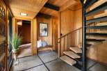Step into a unique entryway featuring a striking spiral staircase and warm wood paneling throughout.