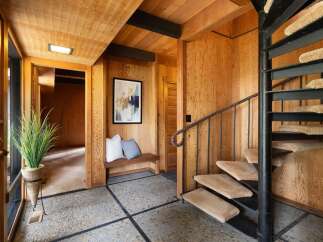 Step into a unique entryway featuring a striking spiral staircase and warm wood paneling throughout.