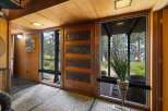 Step into this unique entryway featuring a stunning carved wood door, complemented by natural wood paneling and a textured pebble floor.