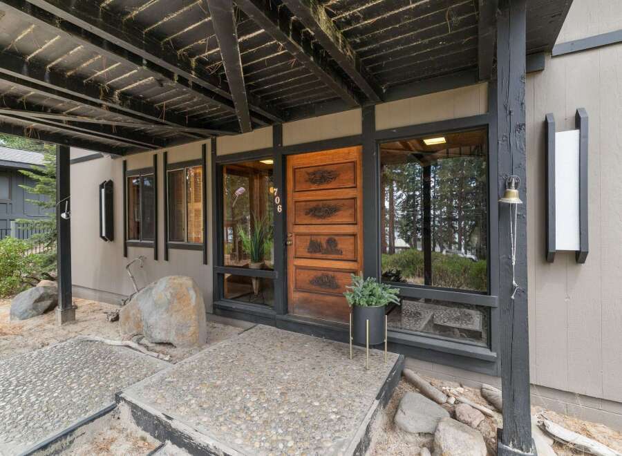 Discover this charming home featuring a unique wooden front door with intricate carvings and a covered entryway.